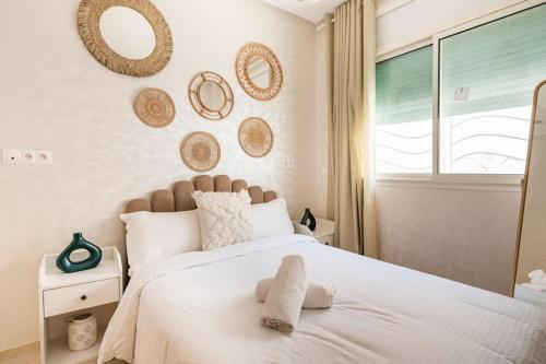 - une chambre avec un lit doté de draps blancs et de miroirs dans l'établissement TT Holidays Cosy Apartment Hassan, à Rabat