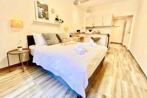 een groot wit bed in een kamer met een keuken bij Cozy Condo in Thessaloniki in Thessaloniki