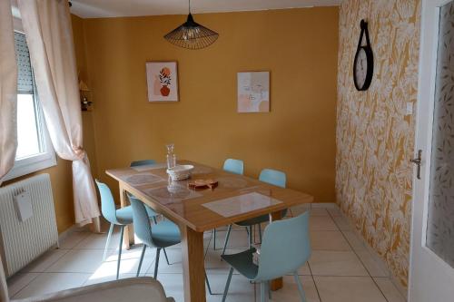 a dining room with a wooden table and blue chairs at Maison Mitoyenne entre les lacs, proche du centre ville de Gérardmer in Gérardmer