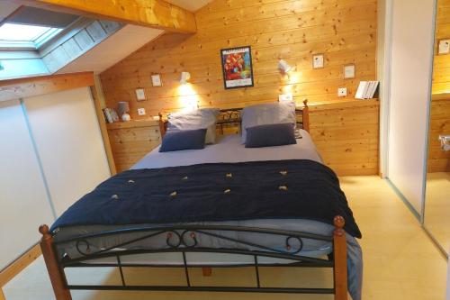 a bedroom with a bed in a room with wooden walls at Maison Mitoyenne entre les lacs, proche du centre ville de Gérardmer in Gérardmer