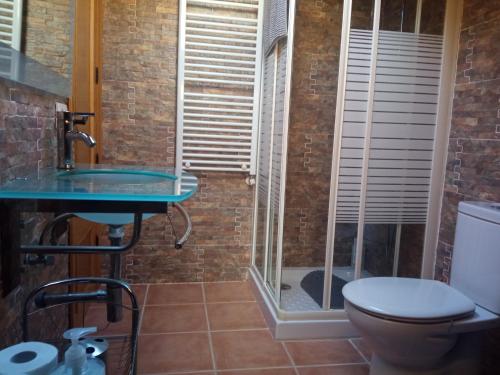 ein Badezimmer mit einem Glaswaschbecken und einem WC in der Unterkunft Casa típica asturiana en Ribota in Celleruelo