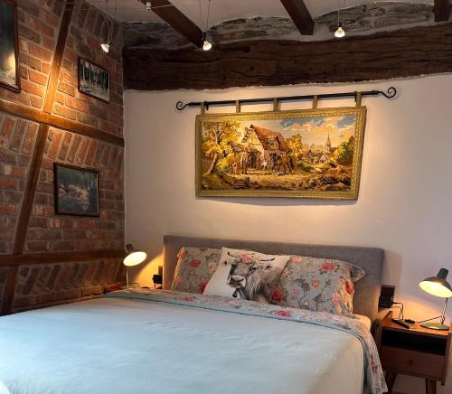 a bedroom with a bed and a painting on the wall at La Remise - Les Chambres in Neufchâteau