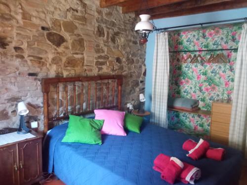 a bedroom with a blue bed with colorful pillows at Casa típica asturiana en Ribota in Celleruelo