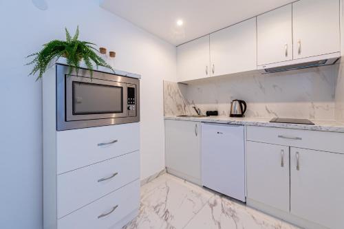 Il comprend une cuisine blanche avec des placards blancs et une télévision. dans l'établissement Apartment with Balcony near Augarten, à Vienne