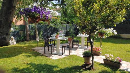 ogród ze stołem, krzesłami i drzewem w obiekcie Villa Liberty B&B w mieście Fano
