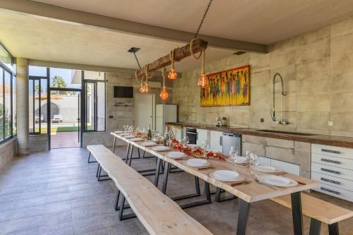 een eetkamer met een lange tafel en banken bij WaterWheel Villa by Fidalsa in Almoradí