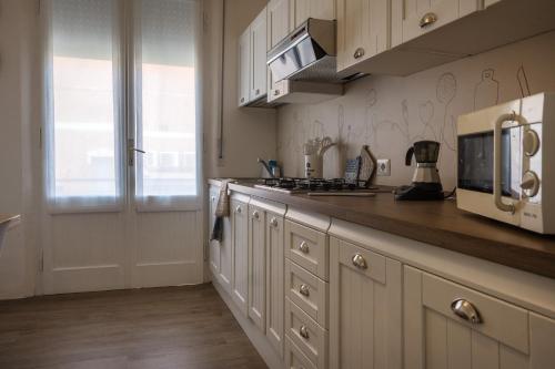 a kitchen with white cabinets and a microwave at Perla Marina Appartamento in Rimini