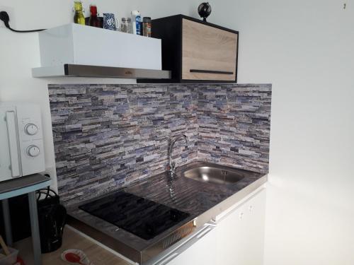 eine Küche mit Spüle und Ziegelwand in der Unterkunft chez LOLO in Saint-Nazaire