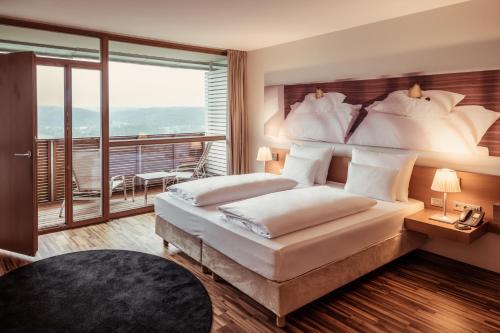 a bedroom with a large bed and a balcony at Falkensteiner Balance Resort Stegersbach - Adults only in Stegersbach