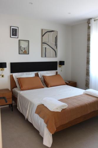 a bedroom with a large bed with white sheets and orange pillows at Villa plain pied vue terrasse in Port-Vendres