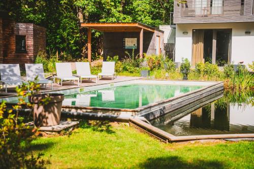 een zwembad in een tuin met stoelen en een huis bij Utopia Hotel - Art & Nature Hotel in Bergen