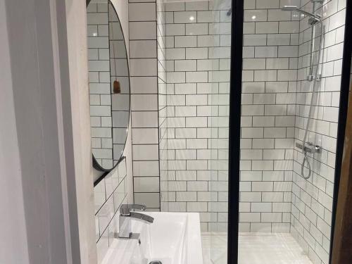 ein Bad mit einem Waschbecken und einer Dusche mit einem Spiegel in der Unterkunft Cosy Cottage (Free parking) in Macclesfield