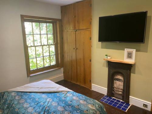a room with a fireplace and a flat screen tv at Cosy Cottage (Free parking) in Macclesfield