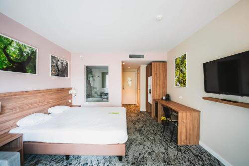 a bedroom with a white bed and a flat screen tv at Utopia Hotel - Art & Nature Hotel in Mons