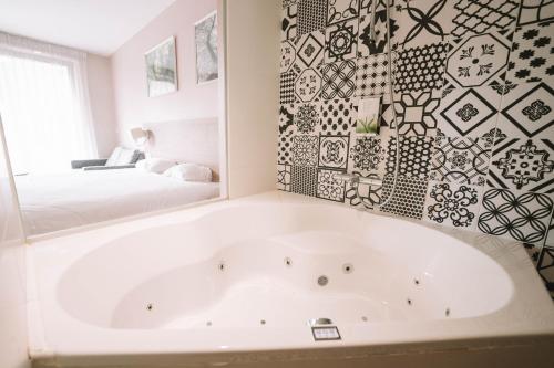 a white bath tub in a room with a bed at Utopia Hotel - Art & Nature Hotel in Mons