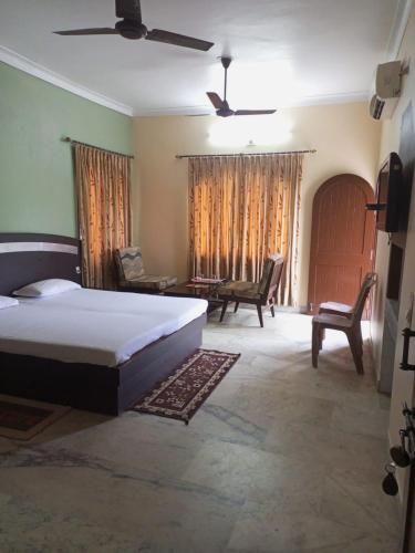 a bedroom with a bed and a couch and chairs at MADHUR RESIDENCY in Puri