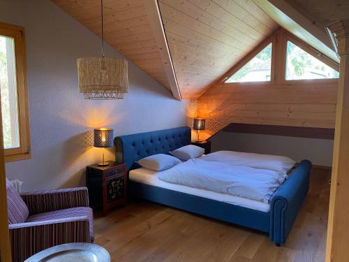 ein Schlafzimmer mit einem blauen Bett im Dachgeschoss in der Unterkunft Chalet Seeblick in Sarnen