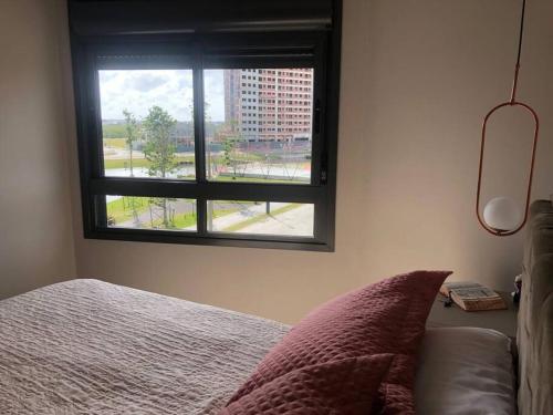 1 dormitorio con cama y ventana en Apartamento no Parque Una com vista espetacular, en Pelotas