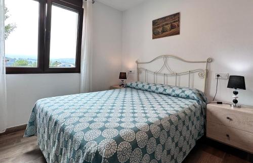 a bedroom with a bed with a blue and white comforter at Apartamentos Rurales Sobremazas in Sobremazas