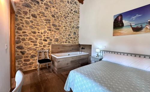 a bedroom with a stone wall and a bed and a tub at Apartamentos Rurales Sobremazas in Sobremazas