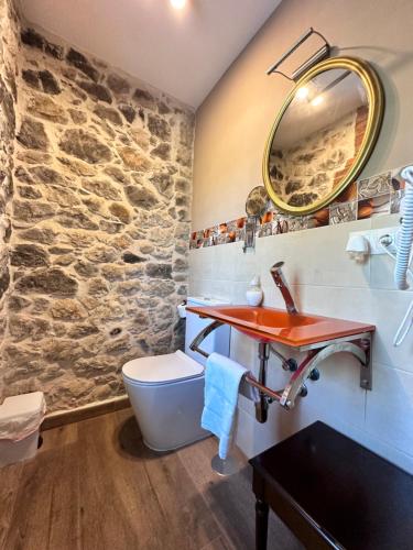 a bathroom with a sink and a stone wall at Apartamentos Rurales Sobremazas in Sobremazas