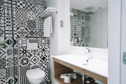 a bathroom with a black and white tiled wall at Utopia Hotel - Art & Nature Hotel in Mons
