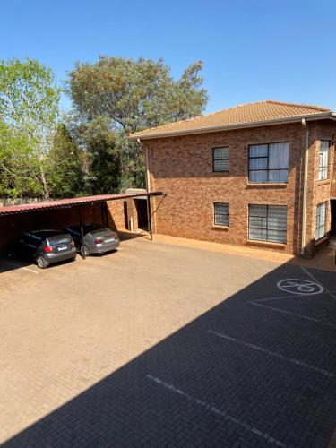 a brick building with two cars parked in a parking lot at AFYZ Mansions in Lenasia