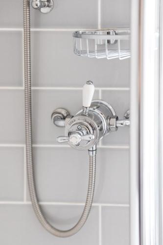 a shower with a shower head in a bathroom at The Georgian House in Alderney