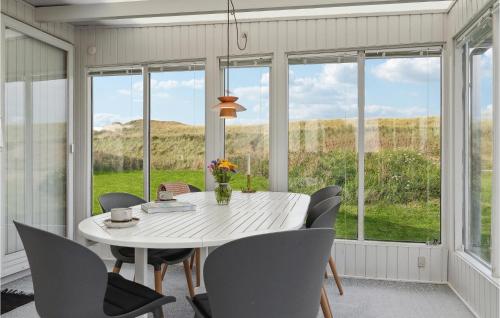 a dining room with a table and chairs and windows at Nice Home In Ulfborg With Wifi in Ulfborg