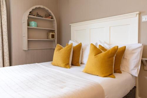 a bedroom with a white bed with yellow pillows at The Georgian House in Alderney