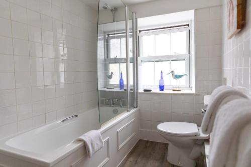 a white bathroom with a tub and a toilet at The Georgian House in Alderney