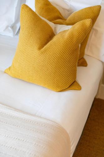 a bed with yellow pillows on it at The Georgian House in Alderney
