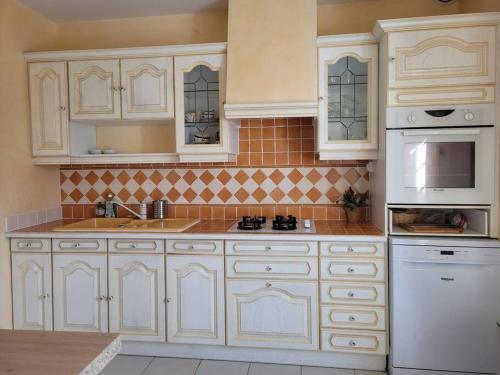 a kitchen with white cabinets and white appliances at Maison au calme à 2 pas du port in Cancale