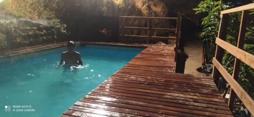 ピエデクエスタにあるCabañas de la lomaの木製の橋の上にあるプールにいる男性