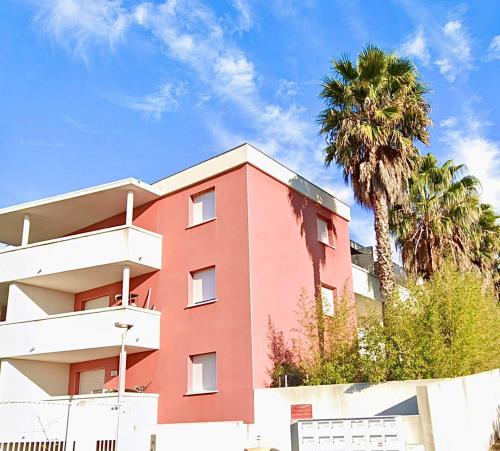 um edifício vermelho com uma palmeira em frente em Appartement meublé T3 Béziers em Béziers