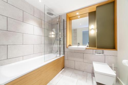 a bathroom with a tub and a sink and a mirror at Amazing 3BDR Duplex wbalcony East London in London