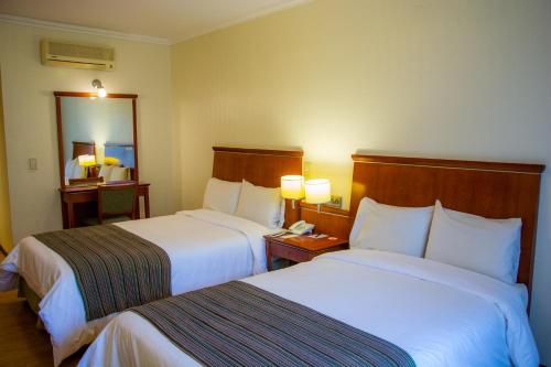 a hotel room with two beds and a mirror at Sol Victoria Hotel SPA & Casino in Victoria