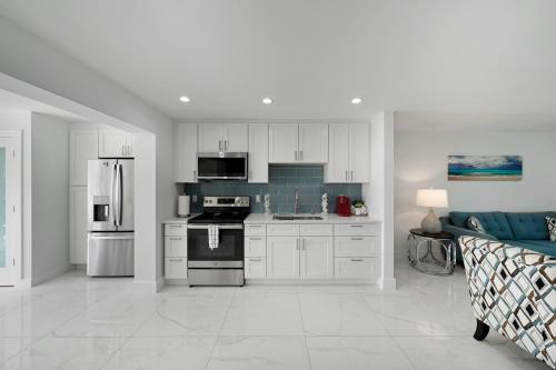 a kitchen with white cabinets and appliances and a couch at Dania Beach Unit 1 By Pmi in Dania Beach