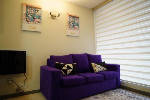 a purple couch in a living room with a window at APART LOMAS DE SAN ANDRÉS centro in Concepción