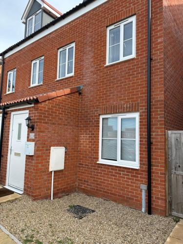 a red brick building with a white door and windows at Beautiful 3bedroom townhouse in a new estate in Great Yarmouth