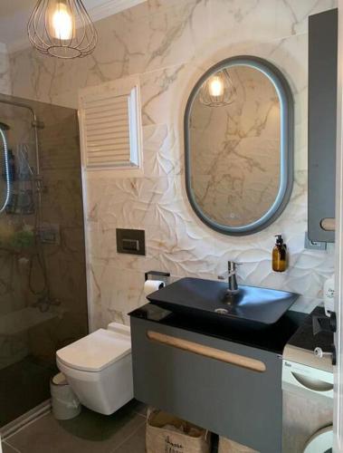 Un baño con lavabo, inodoro y espejo. en Villa Adalin, en Milas