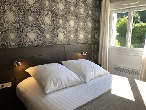 a bedroom with a bed with two pillows and a window at The Originals City, Hôtel du Château, Pontivy (Inter-Hotel) in Pontivy