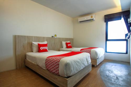 1 dormitorio con 2 camas y almohadas rojas en Super OYO 426 All Day Hostel at Sukhmvit en Bangkok