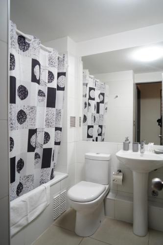 a white bathroom with a toilet and a sink at Apart Lomas de San Andres CENTRO in Concepción
