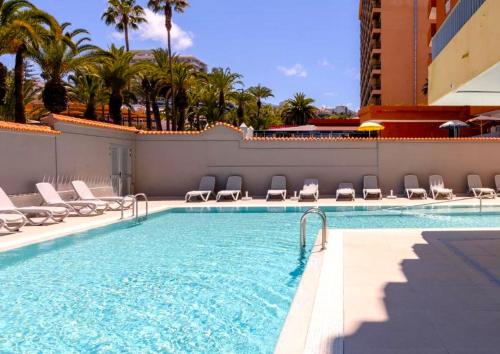 a pool at a hotel with chairs and palm trees at Palmera del Mar in Puerto de la Cruz