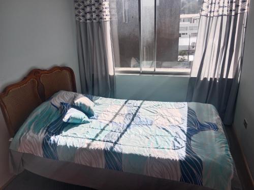 ein kleines Bett in einem Zimmer mit Fenster in der Unterkunft Departamento 3 habitaciones in Quito