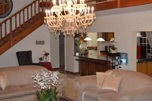 una sala de estar con 2 sofás y una lámpara de araña. en La Barune Guest House, en Tzaneen