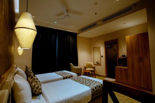 a hotel room with two beds and a desk at Beeza Clubhouse in Kottayam