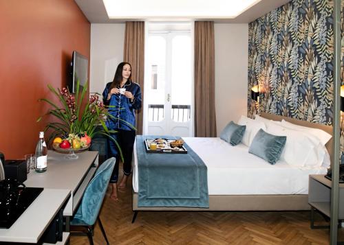 una donna in piedi in una stanza d'albergo con un letto di Hotel Caravita a Roma