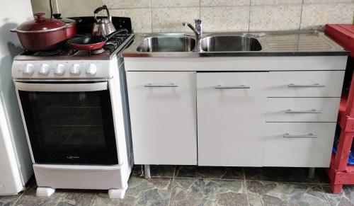 a kitchen with a white stove and a sink at Lo de Facu in Puerto Pirámides